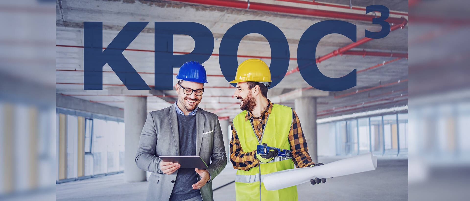Smiling architect in suit with helmet on head talking to contractor while standing in building in construction process. Architect holding tablet.